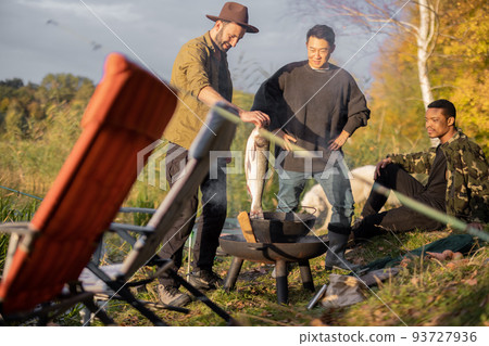 Man putting big fish for cooking Ukha near friends Man putting big fish for cooking Ukha near friends 93727936