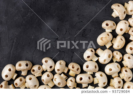 Border of raw champignon mushrooms in the form of skulls. Edible Halloween Concept Border of raw champignon mushrooms in the form of skulls. Edible Halloween Concept 93729084