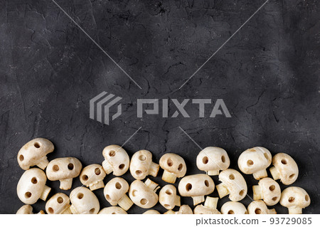 Border of raw champignon mushrooms in the form of skulls. Edible Halloween Concept Border of raw champignon mushrooms in the form of skulls. Edible Halloween Concept 93729085