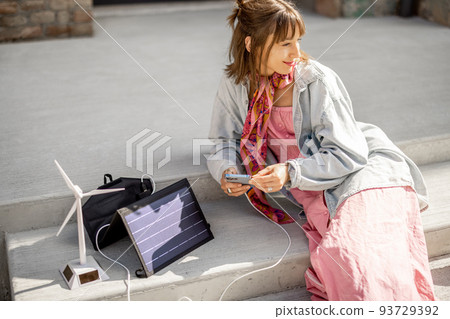 Woman charge phone from a portable solar panel 93729392