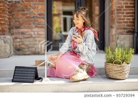 Woman charge phone from a portable solar panel 93729394