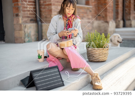 Woman charge phone from a portable solar panel 93729395