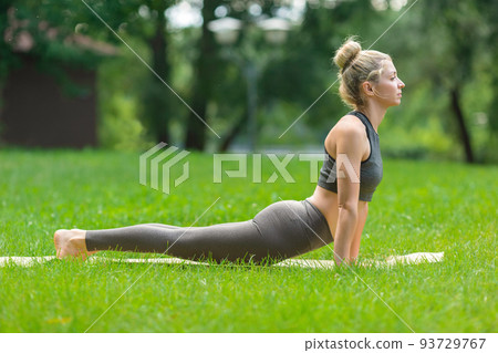 A slender woman on mat in the park, performing yoga on mat A slender woman on mat in the park, performing yoga on mat 93729767