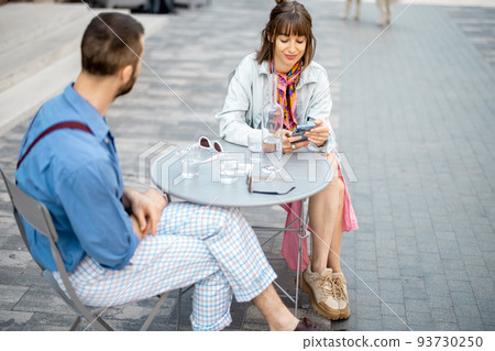 Stylish couple of colleagues have a conversation while sitting at cafe terrace 93730250