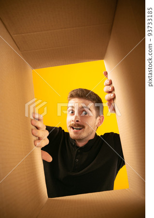Surprising man unpacking opening carton box and looking inside. Delivery, surprise, gift, wow emotions concept. Black friday, holidays, online shopping Surprising man unpacking opening carton box and looking inside. Delivery, surprise, gift, wow emotions concept. Black friday, holidays, online shopping 93733185