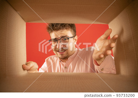 Annoyed man unpacking opening carton box and looking inside. Delivery, surprise, gift, negative emotions concept. Black friday, holidays, online shopping Annoyed man unpacking opening carton box and looking inside. Delivery, surprise, gift, negative emotions concept. Black friday, holidays, online shopping 93733200