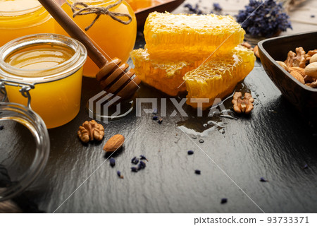 Honeycomb on slate tray with honey and nuts on kitchen table 93733371