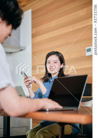 A young woman operating a smartphone during telework A young woman operating a smartphone during telework 93733786