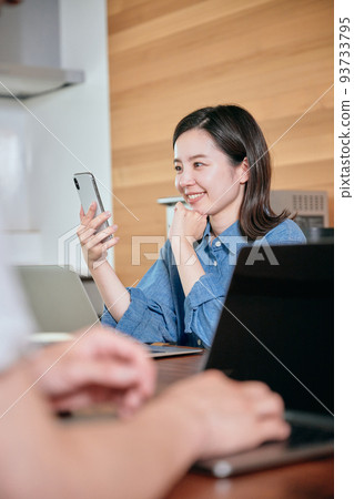 A young woman operating a smartphone during telework A young woman operating a smartphone during telework 93733795