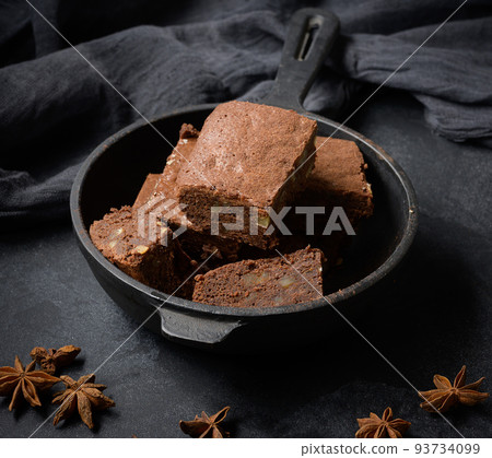 Pieces of baked brownie in a metal black frying pan on the table Pieces of baked brownie in a metal black frying pan on the table 93734099