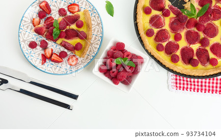 Round quiche with red strawberries and raspberries on a white table Round quiche with red strawberries and raspberries on a white table 93734104