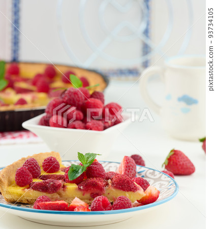 Round quiche with red strawberries and raspberries on a white table 93734105