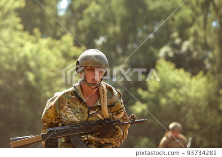 Caucasian Military lady woman in tactical gear posing for photo at summer season. Wearing green camo uniform and assault rifle, in military gear and headset, lady is looking at side Caucasian Military lady woman in tactical gear posing for photo at summer season. Wearing green camo uniform and assault rifle, in military gear and headset, lady is looking at side 93734281
