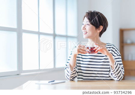 Middle woman drinking tea in the living room Middle woman drinking tea in the living room 93734296