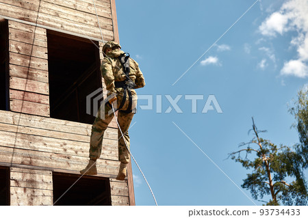 Special forces fighter descends from a skyscraper to storm the apartment. Police, counter terrorism concept. Mixed media Special forces fighter descends from a skyscraper to storm the apartment. Police, counter terrorism concept. Mixed media 93734433
