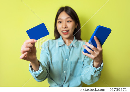 Korean Woman Using Smartphone And Credit Card Shopping, Yellow Background 93739371