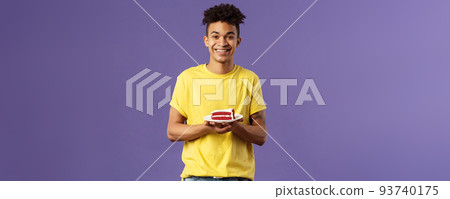 Celebration, party and holidays concept. Portrait of handsome young smiling man, feeling happy likes eating desserts, ordered delivery from local cafe to have some delicious cake, purple background 93740175