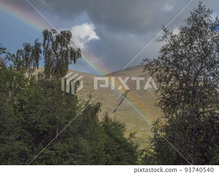 Rainbow over green hills,mountains and birch tree forest at Swedish landscape Lapland at Padjelantaleden hiking trail. Summer overcast day 93740540