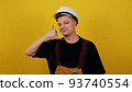 A friendly young worker in a helmet and clothes of a worker of Caucasian appearance shows a gesture - "Call me"" 93740554