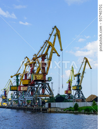 Harbor pier with many cranes and stacks of bulk cargo, coal and wood chips Harbor pier with many cranes and stacks of bulk cargo, coal and wood chips 93740701