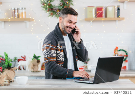 Happy and successful freelance entrepreneur working on laptop at home talking on the phone during the New Year holidays completes the project by deadline Happy and successful freelance entrepreneur working on laptop at home talking on the phone during the New Year holidays completes the project by deadline 93740831