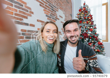 Woman and man at home looking at smartphone camera greet friends with holidays, young family during New Year holidays and Christmas 93740879