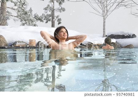 Young female traveler relaxing in a hot spring surrounded by rocks outdoors in winter 93740981