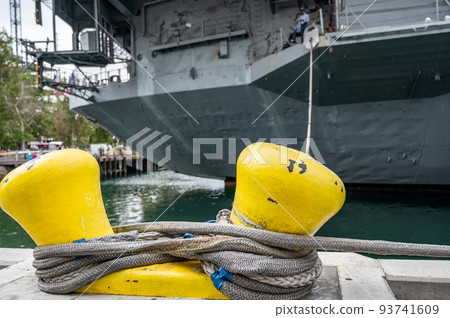 Selective focus on line securing a naval boat to a port bollard. Selective focus on line securing a naval boat to a port bollard. 93741609