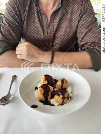 man eating profiteroles at a restaurant table man eating profiteroles at a restaurant table 93742139