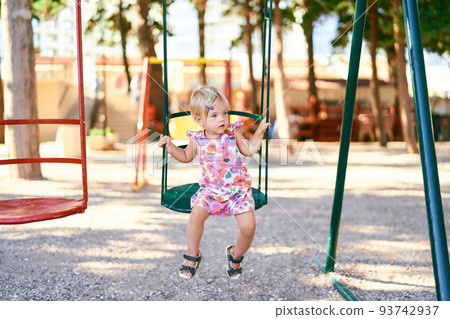 Little girl sits on a swing and looks away 93742937