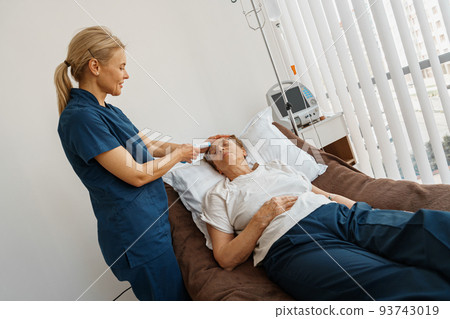 Doctor measures patient's temperature with non-contact thermometer in hospital ward Doctor measures patient's temperature with non-contact thermometer in hospital ward 93743019