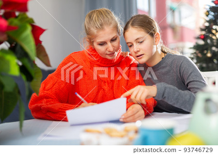 Mom together with daughter write a congratulatory letter during christmas time Mom together with daughter write a congratulatory letter during christmas time 93746729