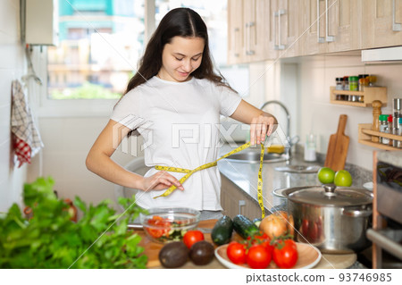 Young cheerful woman taking measurements of body Young cheerful woman taking measurements of body 93746985