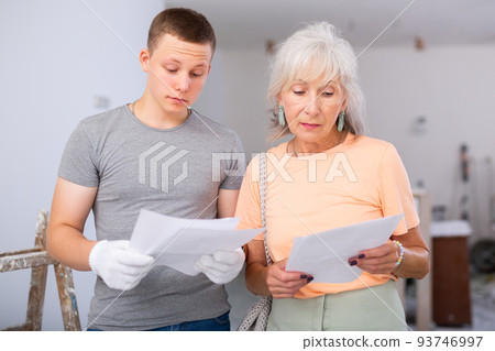 Grandmother and grandson are discussing the drawings of apartment room being renovated Grandmother and grandson are discussing the drawings of apartment room being renovated 93746997