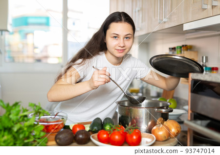 Portrait of young woman cooking at home 93747014