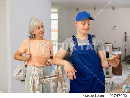 Satisfied young builder received money for his first job as house painter 93747060