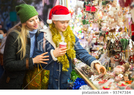Teen girl with her loving mother choosing Xmas decoration on outdoor market 93747384