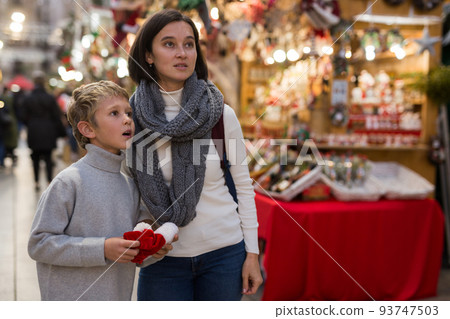 Smiling preteen boy walking with mother at Christmas street market Smiling preteen boy walking with mother at Christmas street market 93747503