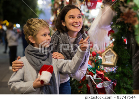 Preteen boy having fun at Christmas fair with mother Preteen boy having fun at Christmas fair with mother 93747544