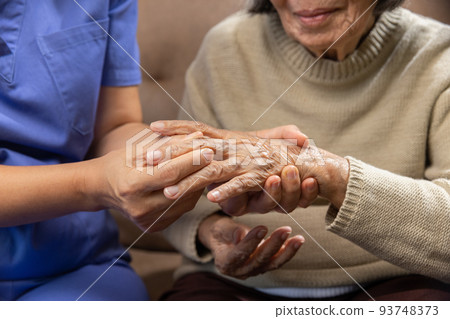 Caregiver massaging wrist of elderly woman in painful swollen gout . 93748373
