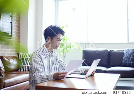 Young Japanese man relaxing in the living room Young Japanese man relaxing in the living room 93748583