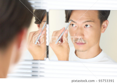 A man who straightens his eyebrows while looking in the mirror Men's beauty image 93753391