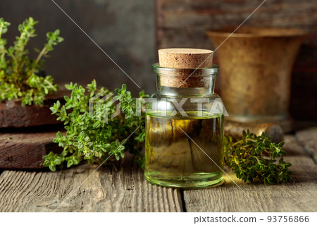 Bottle of thyme essential oil with fresh thyme twigs. Bottle of thyme essential oil with fresh thyme twigs. 93756866