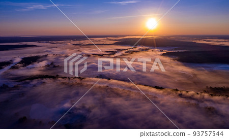 Aerial view of a beautiful summer landscape with a fog while dawn. Photo from drone of a foggy landscape in spring. Top view to land while sunrise. Sun is above the horizon Aerial view of a beautiful summer landscape with a fog while dawn. Photo from drone of a foggy landscape in spring. Top view to land while sunrise. Sun is above the horizon 93757544