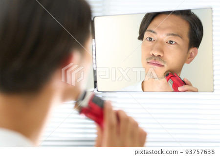 Young man shaving with a shaver men's beauty image 93757638