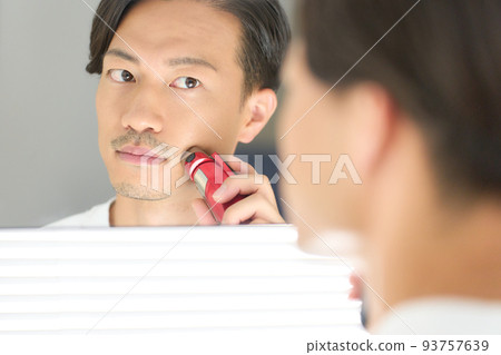 Young man shaving with a shaver men's beauty image 93757639