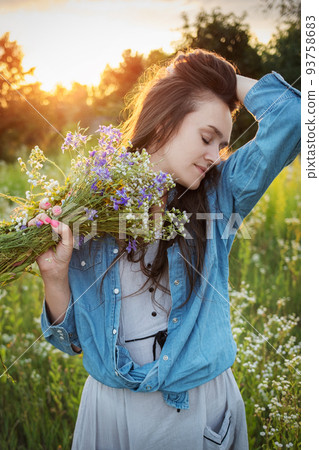 Beautiful girl walking on field on summer with wildflowers. Beautiful girl walking on field on summer with wildflowers. 93758683