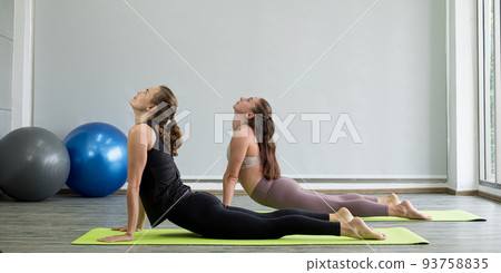 Two young women play yoga stretching, exercise for health in fitness, the concept of physical and mental health care Two young women play yoga stretching, exercise for health in fitness, the concept of physical and mental health care 93758835
