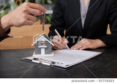 A real estate agent broker hand over the house key to the new owner after completing the signing according to the agreement renting a house and buy the house insurance A real estate agent broker hand over the house key to the new owner after completing the signing according to the agreement renting a house and buy the house insurance 93758883