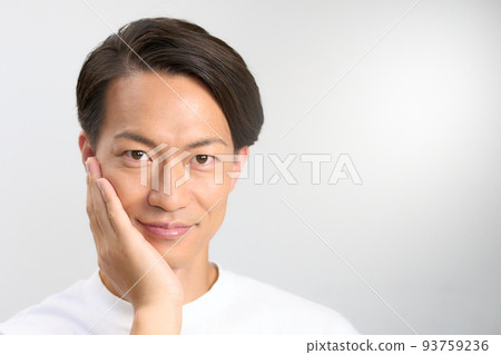 A young man who puts his hand on his cheek and turns his gaze. Men's beauty image 93759236